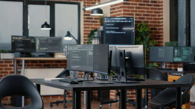 Software development office with multiple monitors displaying code.